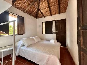 a small bedroom with a bed and a window at Runa Barichara in Barichara