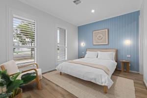 une chambre avec un lit et un mur bleu dans l'établissement Luxe Coastal Retreat, à St Leonards