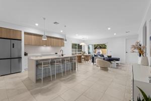 une cuisine ouverte et un salon avec un comptoir et des chaises dans l'établissement Luxe Coastal Retreat, à St Leonards
