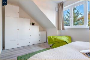 a bedroom with white cabinets and a green chair at Ostseenest Bernstein in Kölpinsee