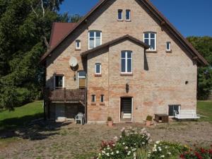 ein großes Backsteinhaus mit einem Hof mit Blumen in der Unterkunft Großbauernhaus in Bentwisch