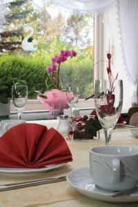 uma mesa com copos de vinho e um guardanapo vermelho em Hotel Pension Haus Irene em Hohwacht