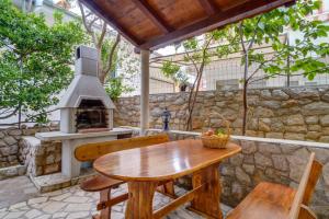 a patio with a wooden table and an outdoor oven at Apartments with a parking space Mali Losinj (Losinj) - 376 in Mali Lošinj