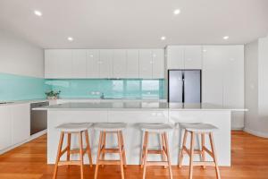een keuken met witte kasten en barkrukken bij The Bluff Villa 4-121 Franklin Pde Encounter Bay - Linen Included in Encounter Bay