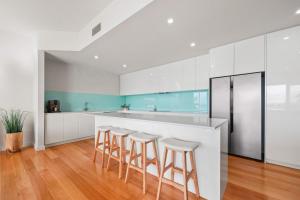 een keuken met witte kasten en een bar met krukken bij The Bluff Villa 4-121 Franklin Pde Encounter Bay - Linen Included in Encounter Bay +22 foto's