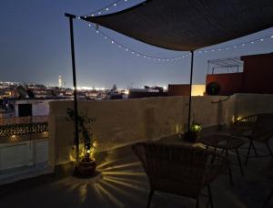 Un patio en la azotea con mesa, sillas y luces. en Cozy Nest, en Sale