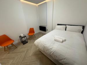een slaapkamer met een wit bed met twee oranje stoelen bij AMD Hotel Wallington SM6 in Wallington
