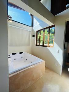 a bathroom with a large white tub in a room at Studio Na Natureza Com Hidro - Baoba Suites in Bombinhas