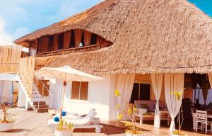 een huis met een rieten dak, stoelen en parasols bij Richland makuti villas watamu in Watamu