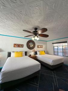 a bedroom with two beds and a ceiling fan at Arrowhead Motel and RV Park in Ruidoso