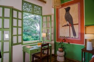 ein Zimmer mit einem Schreibtisch und einem Vogelbild an der Wand in der Unterkunft Baan Samsa in Luang Prabang
