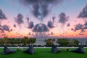 una vista del tramonto da un resort con erba e panchine di Sumitra Luxury Villas & Resort by Pramana a Sanur