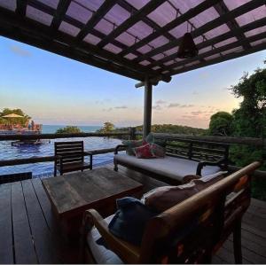 un portico con una panca e un tavolo e una vista sull'acqua di Suite com jacuzzi privativa a Maceió