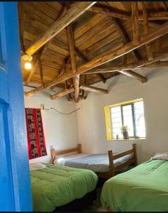 2 bedden in een kamer met houten plafonds bij Coco's vibes in Ollantaytambo