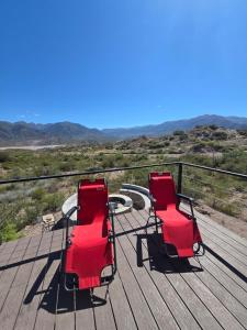 due sedie rosse sedute sopra un ponte di legno di Altos Dique Potrerillos a Potrerillos