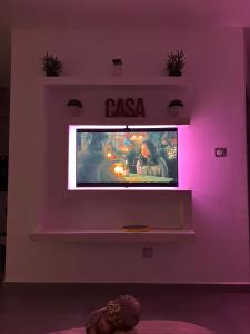 een tv in een kamer met een paarse muur bij Charmante maison avec jacuzzi in Le Gosier