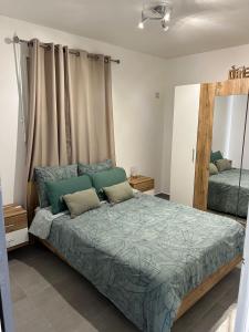 een slaapkamer met een groot bed met twee kussens bij Charmante maison avec jacuzzi in Le Gosier