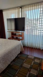 een slaapkamer met een bed en een flatscreen-tv bij Departamento Centro de Viña in Viña del Mar