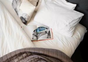 a bed with white pillows and a book on it at Spice On Broadway in Sydney