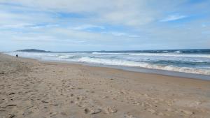 een persoon die op een strand loopt met de oceaan bij Casa Ilha comprida 2 quartos yemar in Ilha Comprida