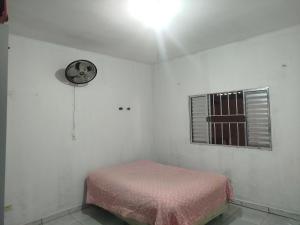 una stanza bianca con un letto e una finestra di Casa da Cris a Itanhaém