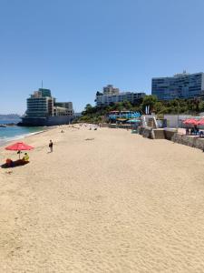 een strand met mensen en parasols en de oceaan bij Departamento Centro de Viña in Viña del Mar