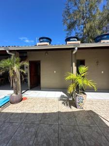 a house with two palm trees in front of it at Casa Aiyra in São Miguel dos Milagres