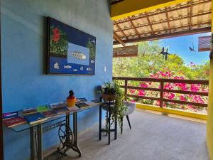 een kamer met een bureau en een balkon met bloemen bij Quintal da Espera - Praia de Itacimirim in Camaçari +11 foto's