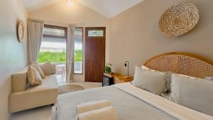 ein Schlafzimmer mit einem Bett und einer Couch und einem Fenster in der Unterkunft Uluwatu Ocean Front Surf Suite in Uluwatu