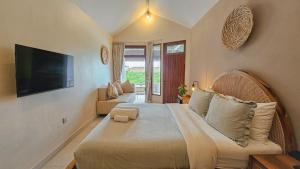 ein Schlafzimmer mit einem großen Bett und einem Fernseher an der Wand in der Unterkunft Uluwatu Ocean Front Surf Suite in Uluwatu
