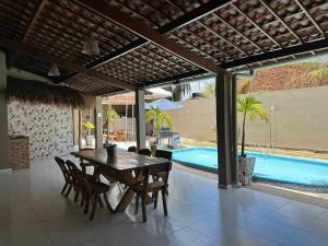 a dining room with a table and chairs and a pool at Casa Aiyra in São Miguel dos Milagres +3 photos