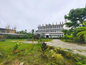 a large white building in the middle of a park at Taj Heritage Hotel and Restaurant - Premium & Budget Rooms in Jorhāt