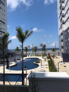 uitzicht op een zwembad met palmbomen en de oceaan bij Beachfront apartment with swimming pool in Mongaguá