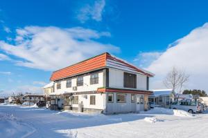 ein weißes Gebäude mit orangefarbenem Dach im Schnee in der Unterkunft KING DEER - Vacation STAY 67718v in Higashikawa