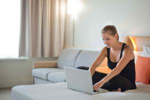 a woman sitting on a bed using a laptop computer at Novotel Manchester West in Worsley +110 photos