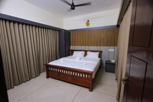 a bedroom with a bed with a wooden wall at G' de CASA in Varkala +12 photos