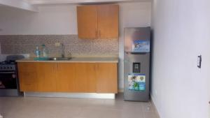 a kitchen with a stainless steel refrigerator and wooden cabinets at Alojamiento M&M in Los Paredones