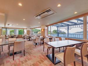 ein Restaurant mit Tischen und Stühlen und großen Fenstern in der Unterkunft Toba Wan Wan Paradise Hotel in Toba