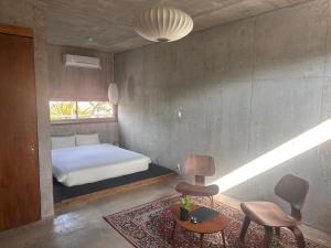 ein Schlafzimmer mit einem Bett, einem Stuhl und einem Tisch in der Unterkunft Stay Hotel Nakijin in Nakijin