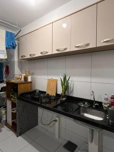 a kitchen with white cabinets and a black counter top at Village do Sol 3 - Apt compartilhado in Maioba