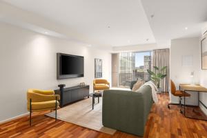 a living room with a couch and a tv at Nolo Apartments Lonsdale St in Melbourne