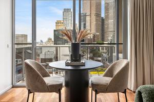 a room with a table and chairs and a large window at Nolo Apartments Lonsdale St in Melbourne