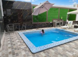 een vrouw in een zwembad met een paraplu bij la punta nueva en Camaná in La Punta