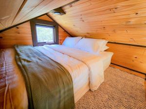 a bed in a log cabin with a window at Anakie Gorge Getaway Tiny House 1 by Tiny Away in Staughton Vale