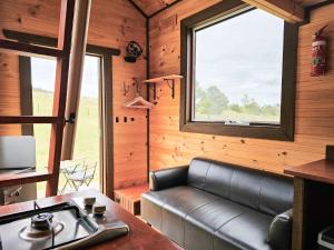 a living room with a leather couch and a window at Anakie Gorge Getaway Tiny House 1 by Tiny Away in Staughton Vale