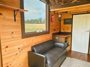 a leather couch in a tiny house with a window at Anakie Gorge Getaway Tiny House 1 by Tiny Away in Staughton Vale