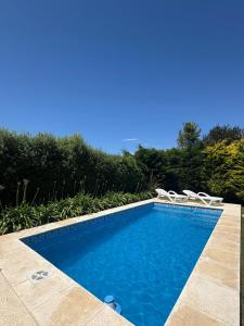 een zwembad met twee witte stoelen ernaast bij Atardecer de San Benito in La Estafeta