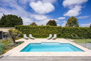 a swimming pool with two lounge chairs and a swimming pool at Play on Balcombe in Mount Martha +34 photos