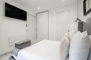 a white bedroom with a bed and a flat screen tv at Casa Ama in Mexico City