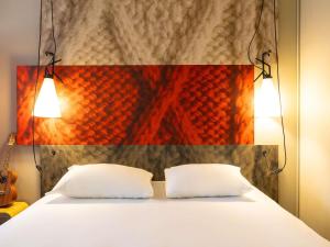 a bed with two white pillows in front of a wall at ibis Gent Centrum Opera in Ghent +51 photos